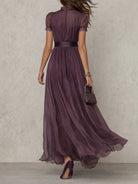 Side profile of a model wearing the Evadne purple chiffon lace maxi dress, highlighting its elegant drape and defined waist.