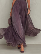 Lifestyle shot of the Evadne purple chiffon lace maxi dress in a garden setting, emphasizing its suitability for outdoor events.