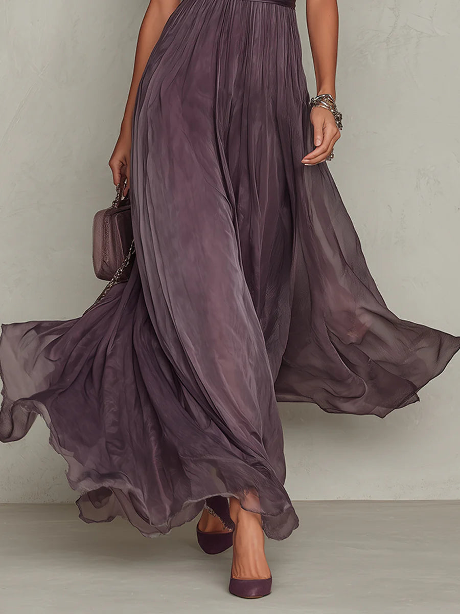 Lifestyle shot of the Evadne purple chiffon lace maxi dress in a garden setting, emphasizing its suitability for outdoor events.