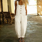 A model in white Hadley soft denim overalls, seated casually, illustrating the freedom of movement and relaxed styling.