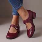 Close-up of the adjustable buckle strap and side cut-outs on a stylish burgundy Mary Jane shoe, highlighting comfort features.