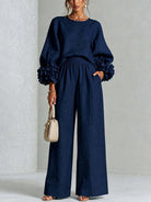 Lifestyle shot of a woman seated in green wide-leg trousers, perfect for a relaxed occasion or long lunch.