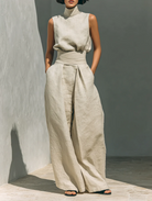 Close-up detail of the high fixed waistband and stylish front pleats on the cotton trousers.