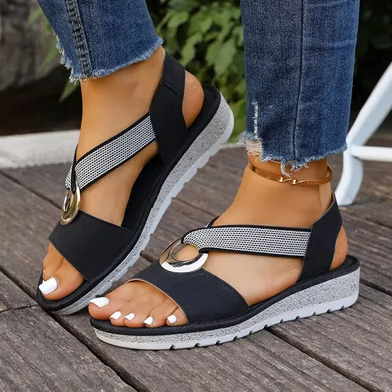 Artemis sandals in khaki on a wooden deck.