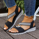 Artemis sandals in khaki on a wooden deck.