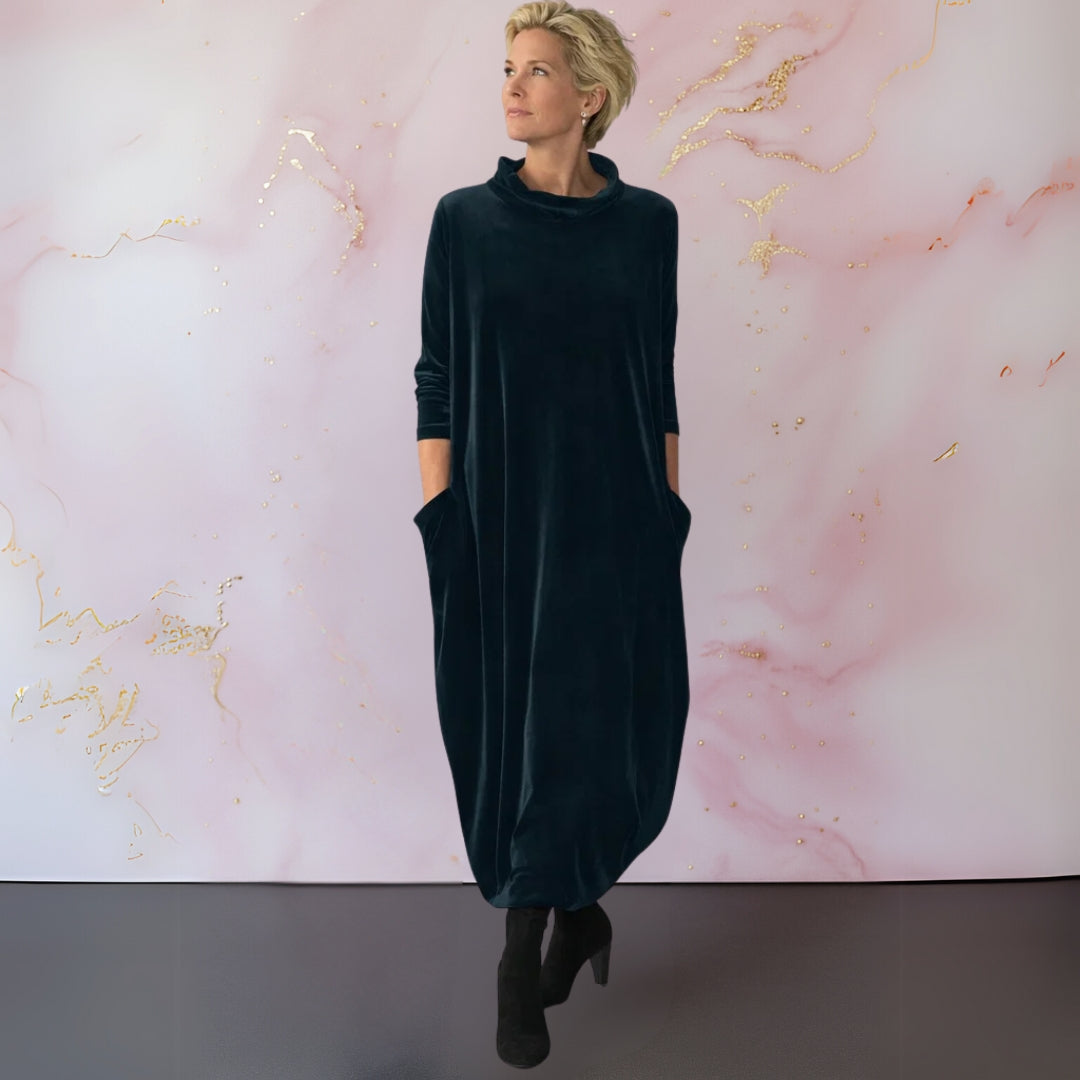 Front view of a woman wearing the Leona velvet maxi dress in dark green, showcasing its elegant draped silhouette.