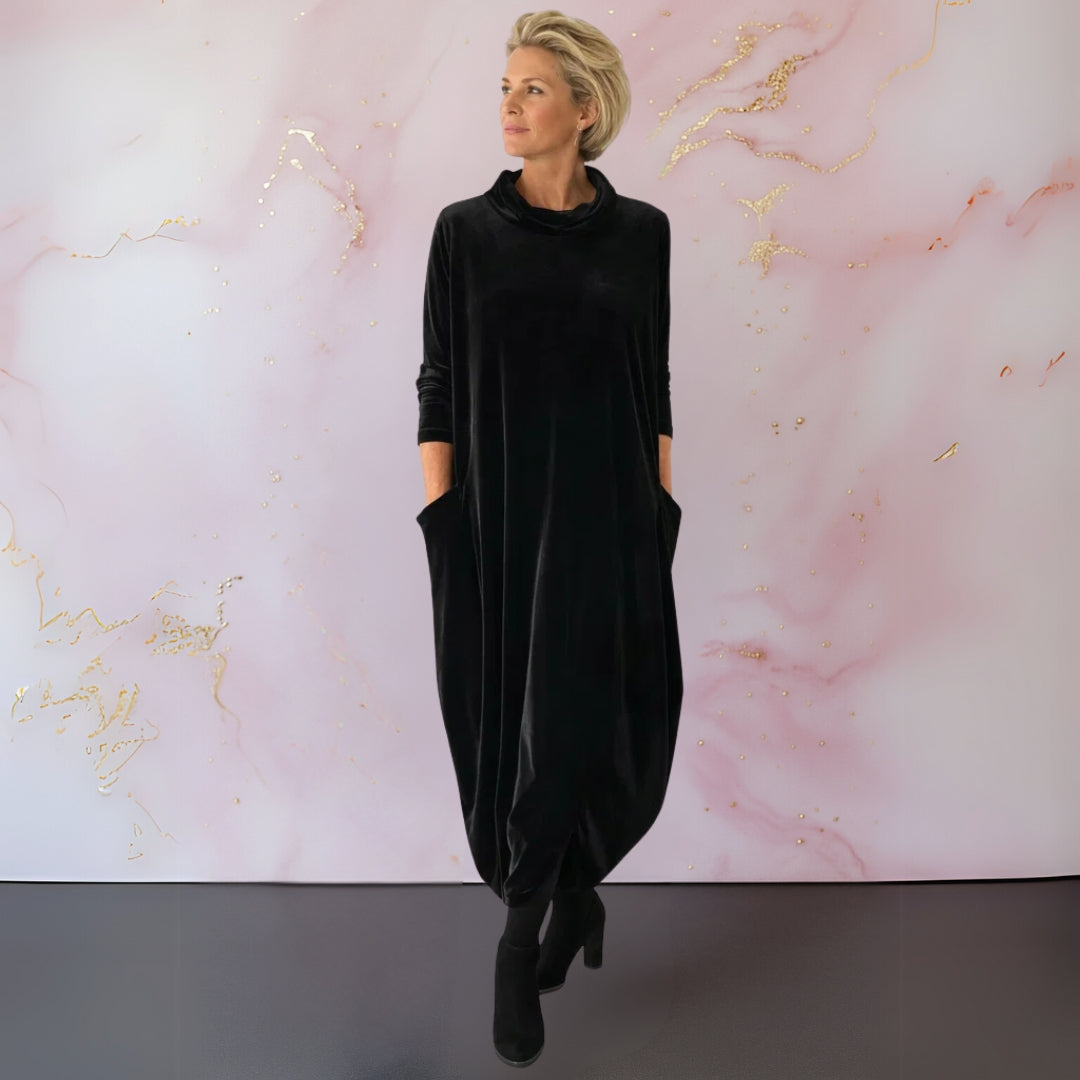 Full-length shot of the Leona velvet maxi dress in blue, styled with ankle boots for a chic daytime look.