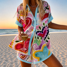 Front view of the Lysette Watercolor Heart Camp Shirt, showcasing its white light weave fabric adorned with red, pink, and teal watercolor hearts and sky-blue trim on the collar and placket.