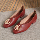 Close-up detail of the striking gold-tone circular accent on a beige square-toe flat, adding a touch of elegance.