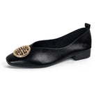 A pair of classic black square-toe flats displayed next to casual denim jeans, illustrating versatile styling.