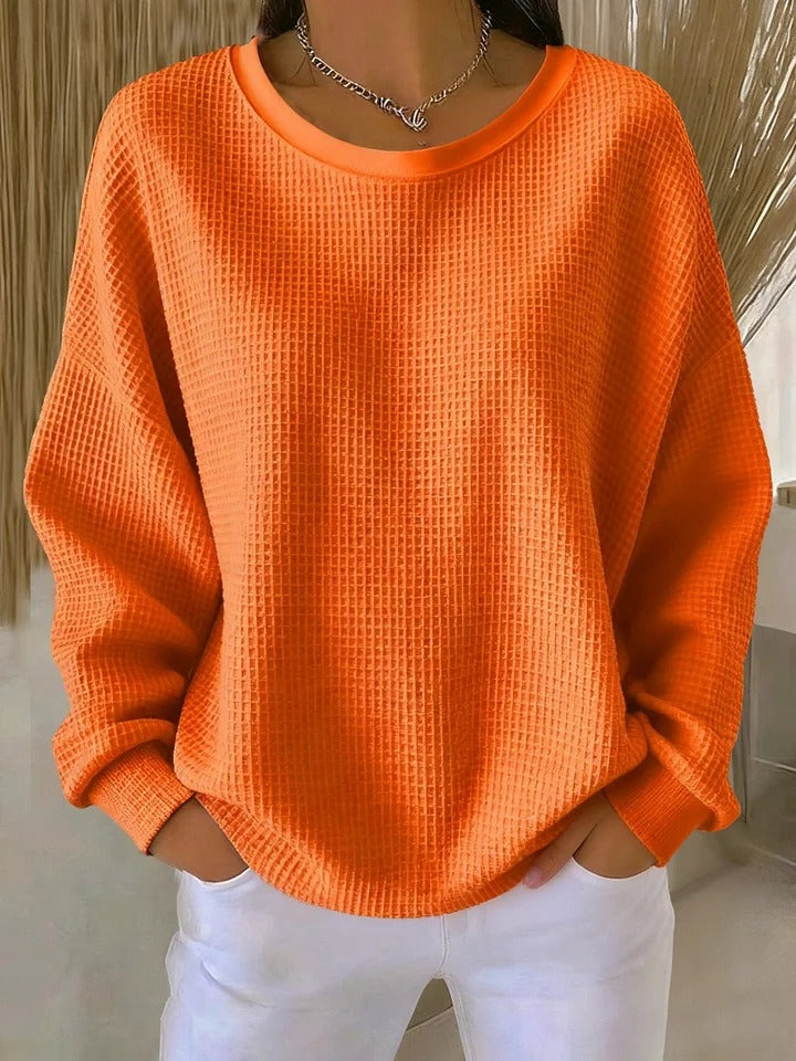 Detail shot of the sleeve cuff on the Odette knit sweater in orange, emphasizing its unpretentious finish.