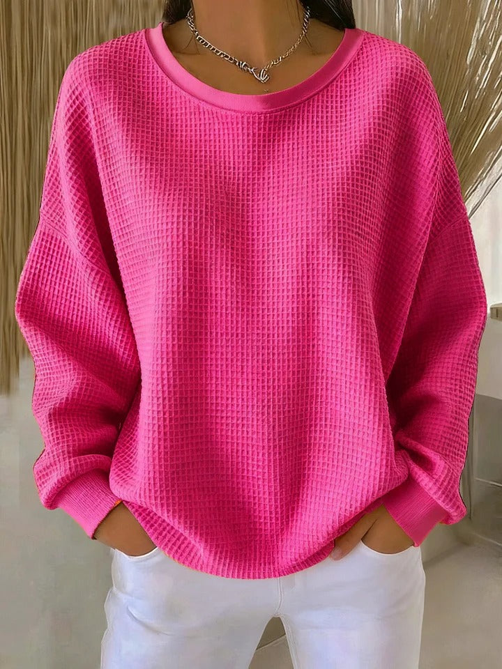 A model smiling while wearing the Odette knit sweater in fuchsia, showcasing comfort and confidence.