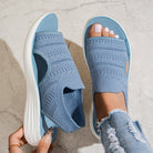 Woman wearing dark blue platform sandals, walking casually on a paved pathway, showing natural movement.